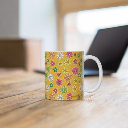 Daffodil a yellow-orange porcelain cup with floral print on desk.