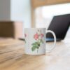 A graceful pink Marie Antoinette Rose on a white porcelain tea mug that stands on a desk