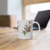 A stylish red Alpine Rose on a white porcelain cup that stands on a desk