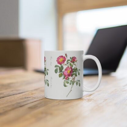 An appealing red Rosa Pimpinellifolia rose on a white porcelain cup that stands on a desk